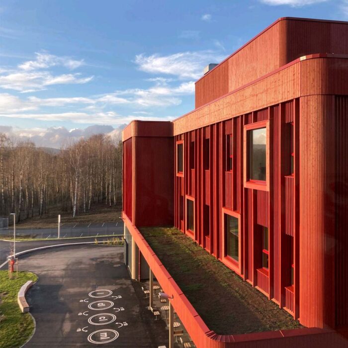 Moderne Schule in Lillestrøm mit roter Holzfassade, gebaut mit KNAPP-Produkten Ricon S und Megant, fotografiert von Nils Petter.