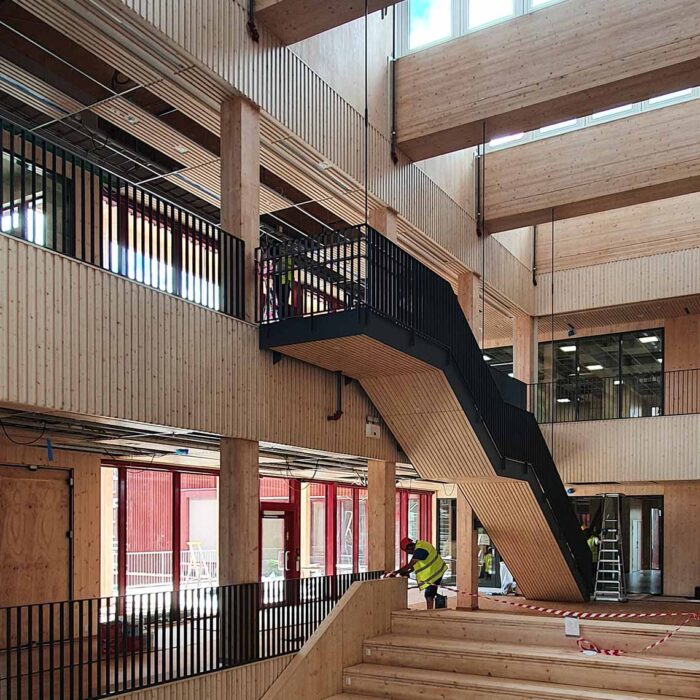Helle und moderne Schularchitektur in Lillestrøm mit Holzbauweise, großen offenen Bereichen und Treppen. Errichtet mit KNAPP-Verbindern Ricon S und Megant. Fotografie: Nils Petter.